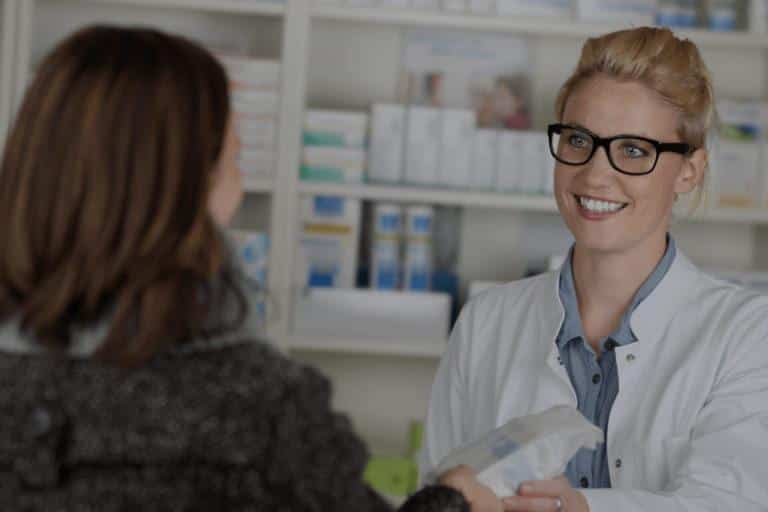 Conseils du pharmacien Pharmacienne souriante qui donne des médicaments à une cliente